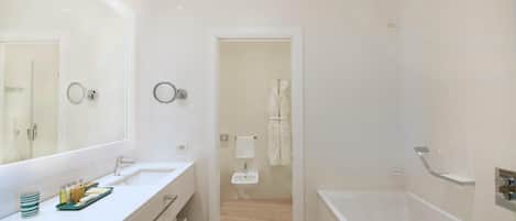 Un baño moderno con un espejo grande, dos lavamanos, una bañera y una ducha.