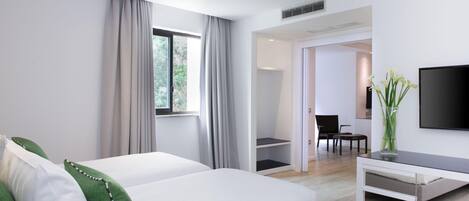 A modern hotel room with a bed, a desk, a chair, a TV, and a view of the outdoors.