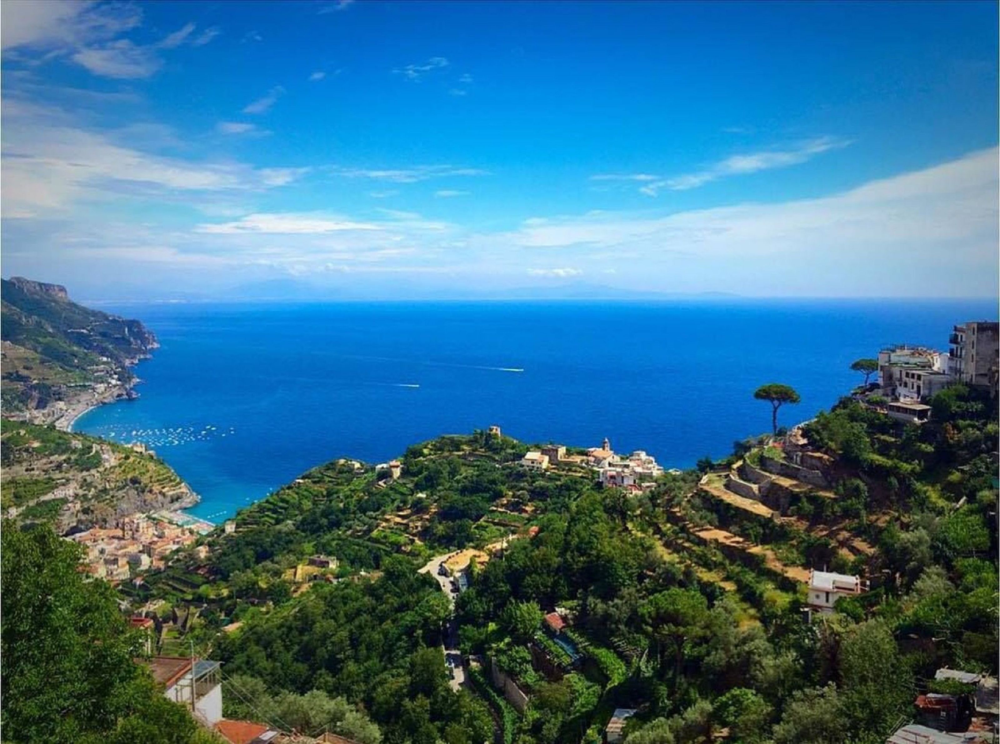 Un pueblo costero con casas escalonadas, una vista despejada del mar y una costa distante.