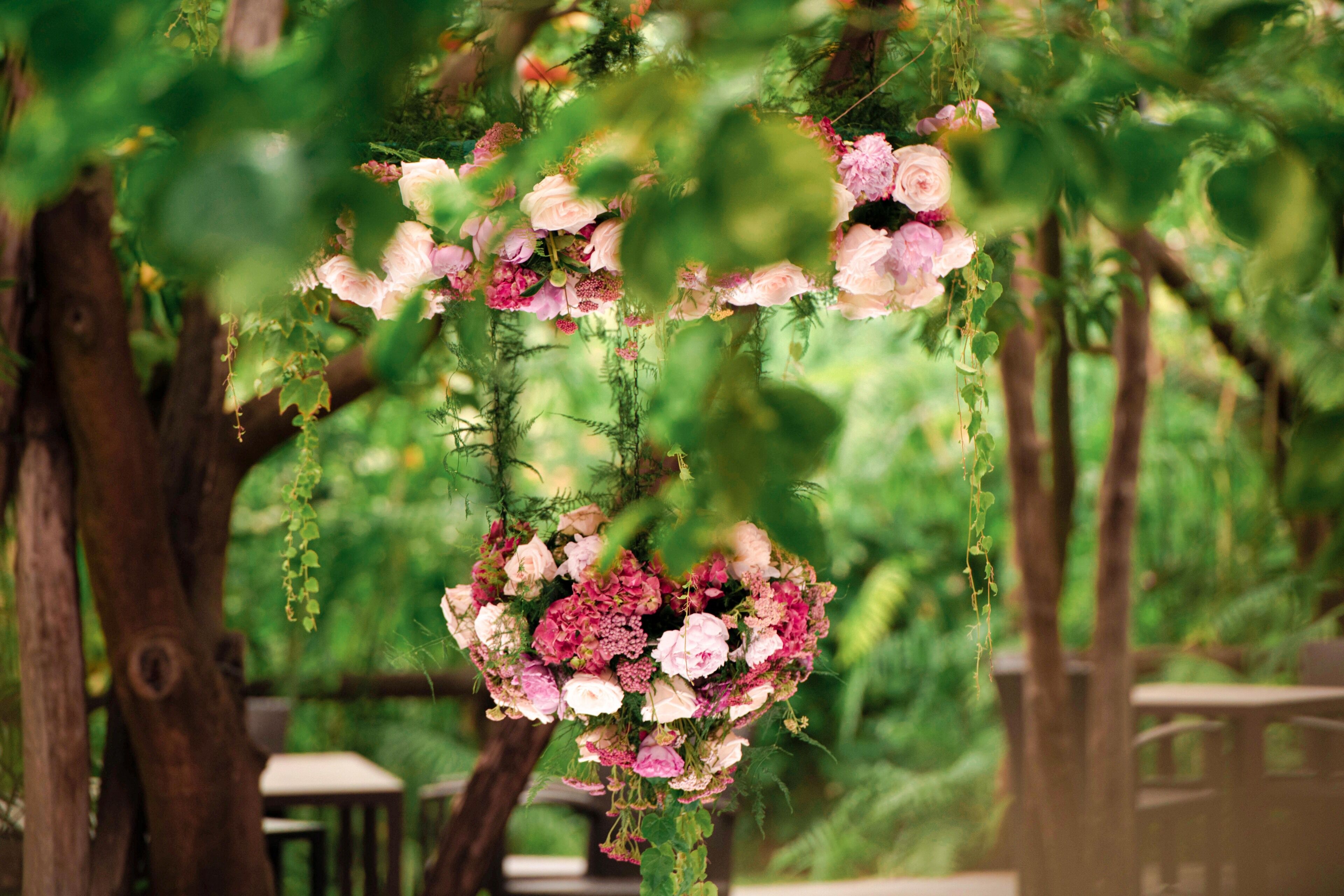 A hanging floral arrangement in a lush, green outdoor setting.