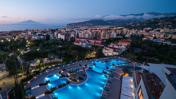 Ein Resort mit mehreren Schwimmbecken, Blick auf die Stadt und einem Bergpanorama.