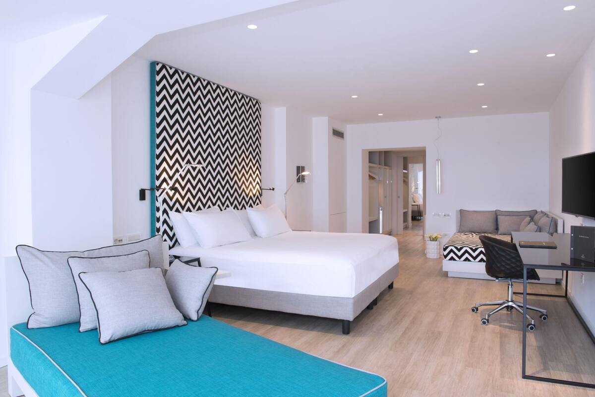 Une chambre d’hôtel moderne équipée d’un lit, d’un bureau et d’un canapé.
