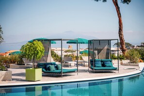 Ein Poolbereich mit Liegestühlen, Sonnenschirmen und Blick auf das Meer.