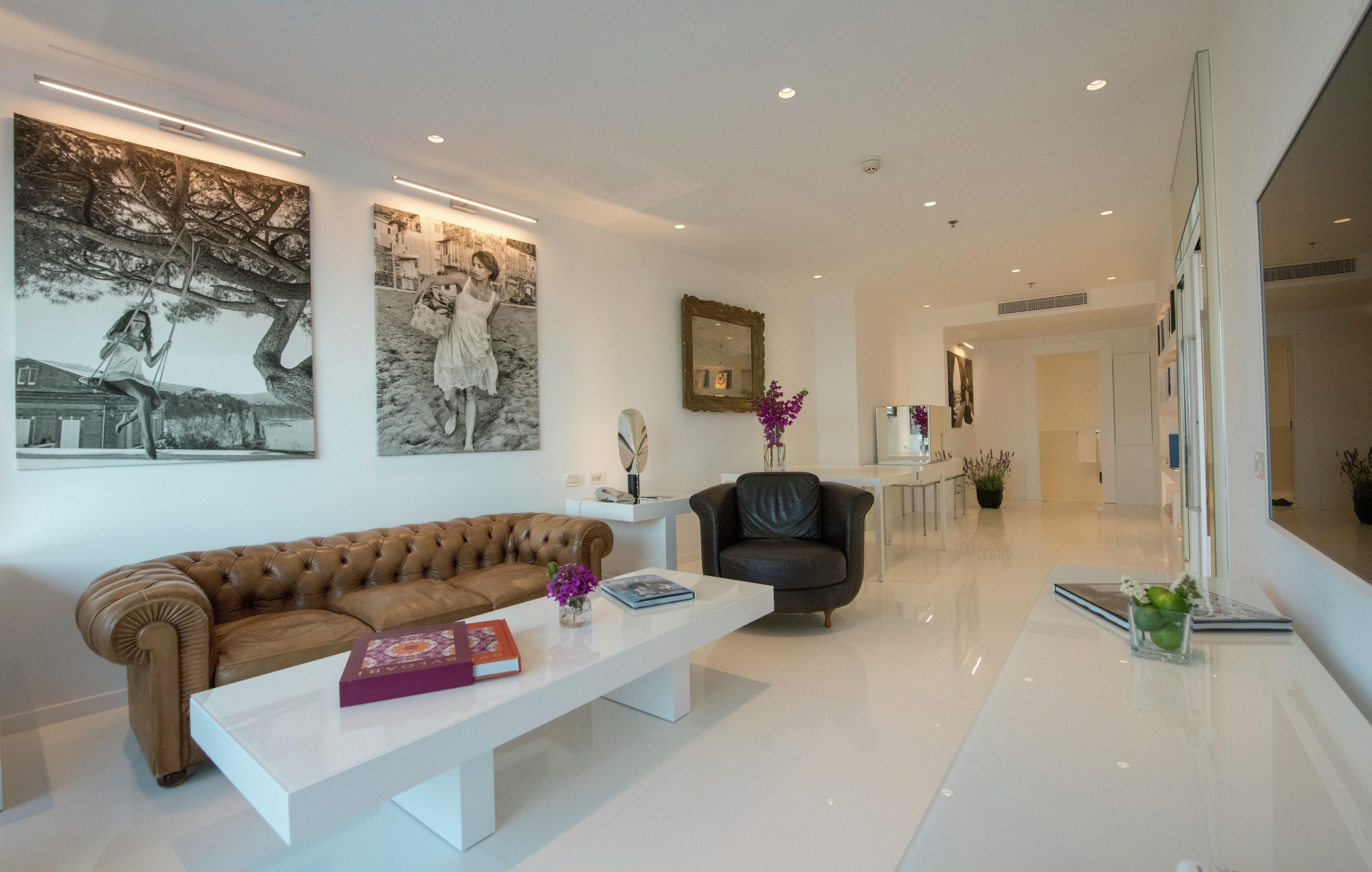 A modern living room with a leather sofa, a white coffee table, and artwork on the walls.