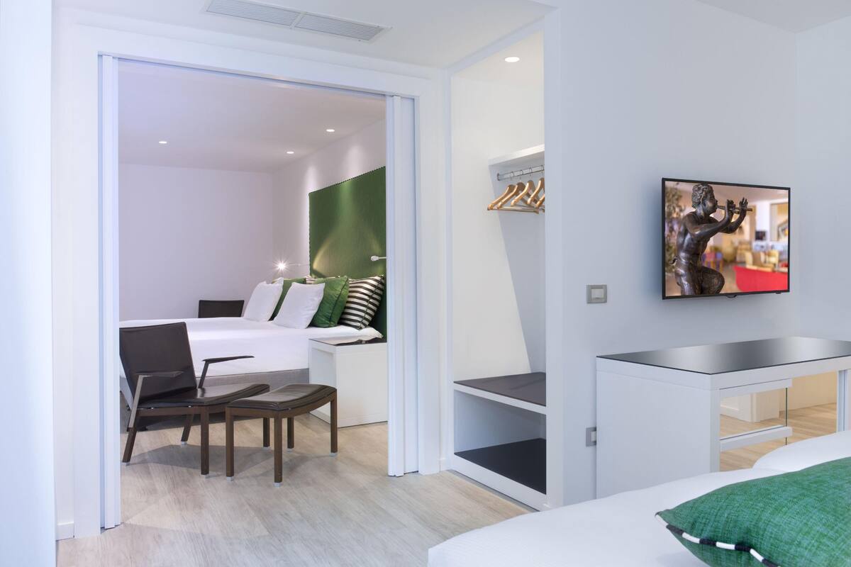 Une chambre d’hôtel moderne équipée d’un lit, d’un bureau, d’une chaise, d’une télévision et d’un rideau vert.