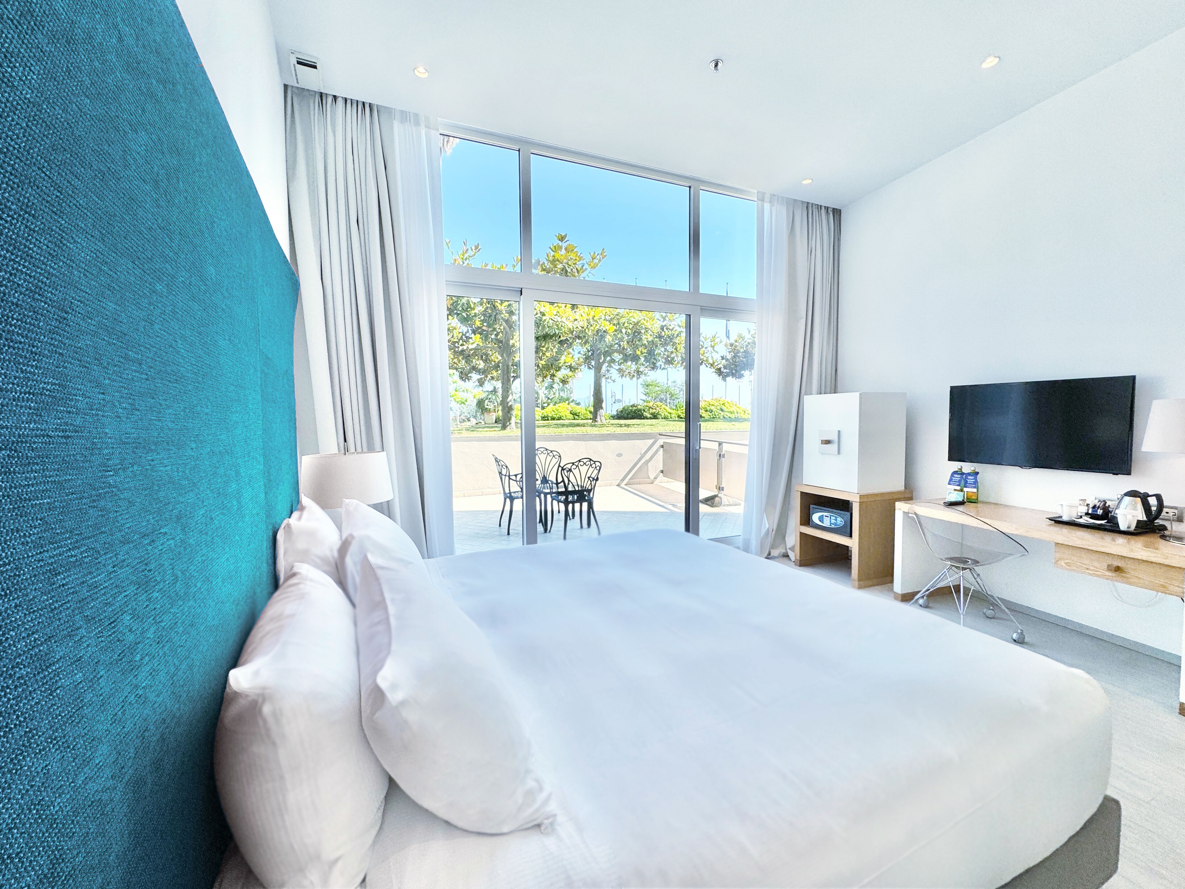 Een moderne hotelkamer met een groot bed, een bureau, een televisie en uitzicht op de omgeving.
