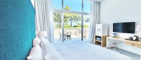 Een moderne hotelkamer met een groot bed, een bureau, een televisie en uitzicht op de omgeving.