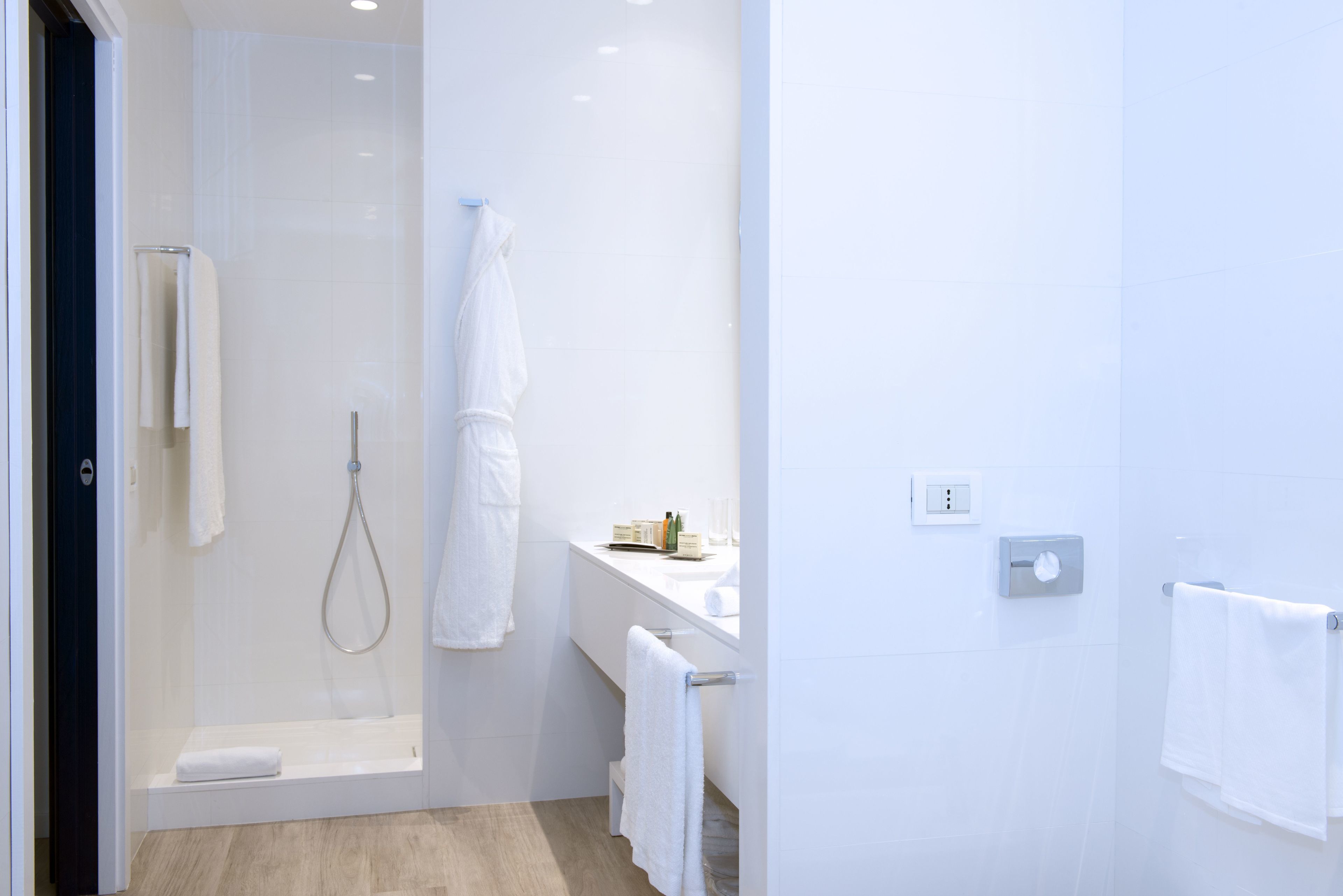 Een moderne badkamer met een douchecabine van glas, een witte wasbak en een handdoekhouder.