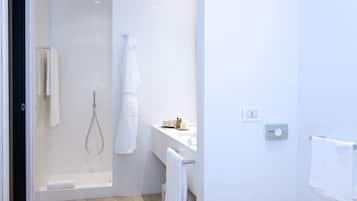 Een moderne badkamer met een douchecabine van glas, een witte wasbak en een handdoekhouder.