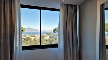 Una habitación con ventanas amplias que ofrecen vistas a un paisaje urbano, montañas y una masa de agua.
