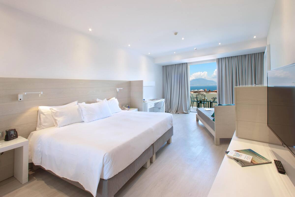 Une chambre d’hôtel avec un grand lit, un bureau, une chaise et un téléviseur.