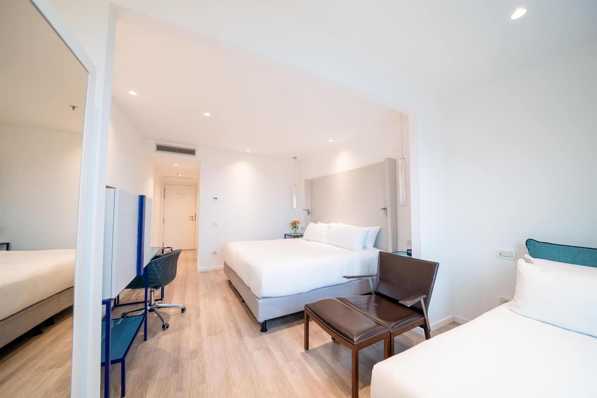 Une chambre d’hôtel avec un lit, un bureau, une chaise et une petite table.