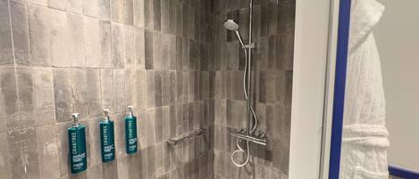 A shower with a rain showerhead, a handheld showerhead, and a handheld scrubber.
