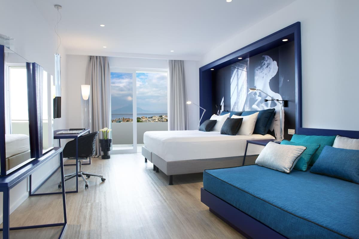 Une chambre d’hôtel moderne, dotée d’un grand lit, d’un canapé, d’un bureau et offrant une vue sur la ville.