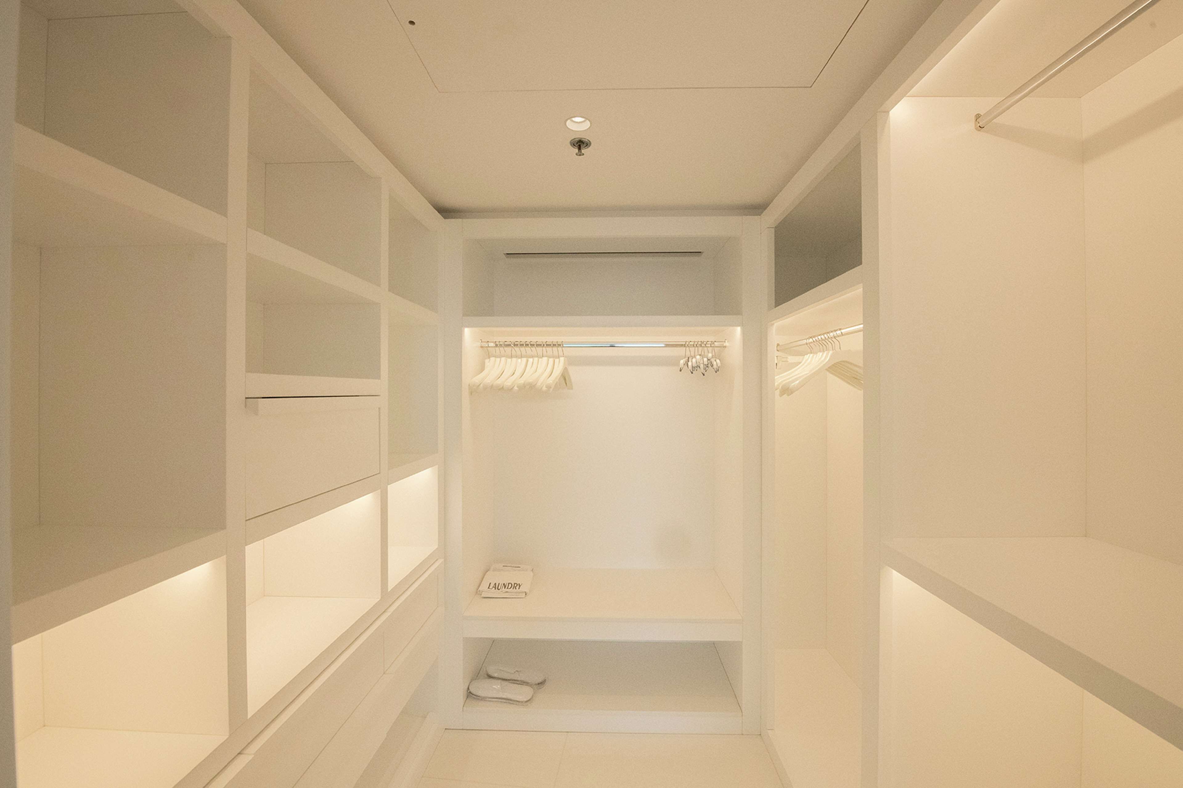 Un vestidor amplio con estantes múltiples y espacio para colgar, una báscula integrada y un cesto de ropa.