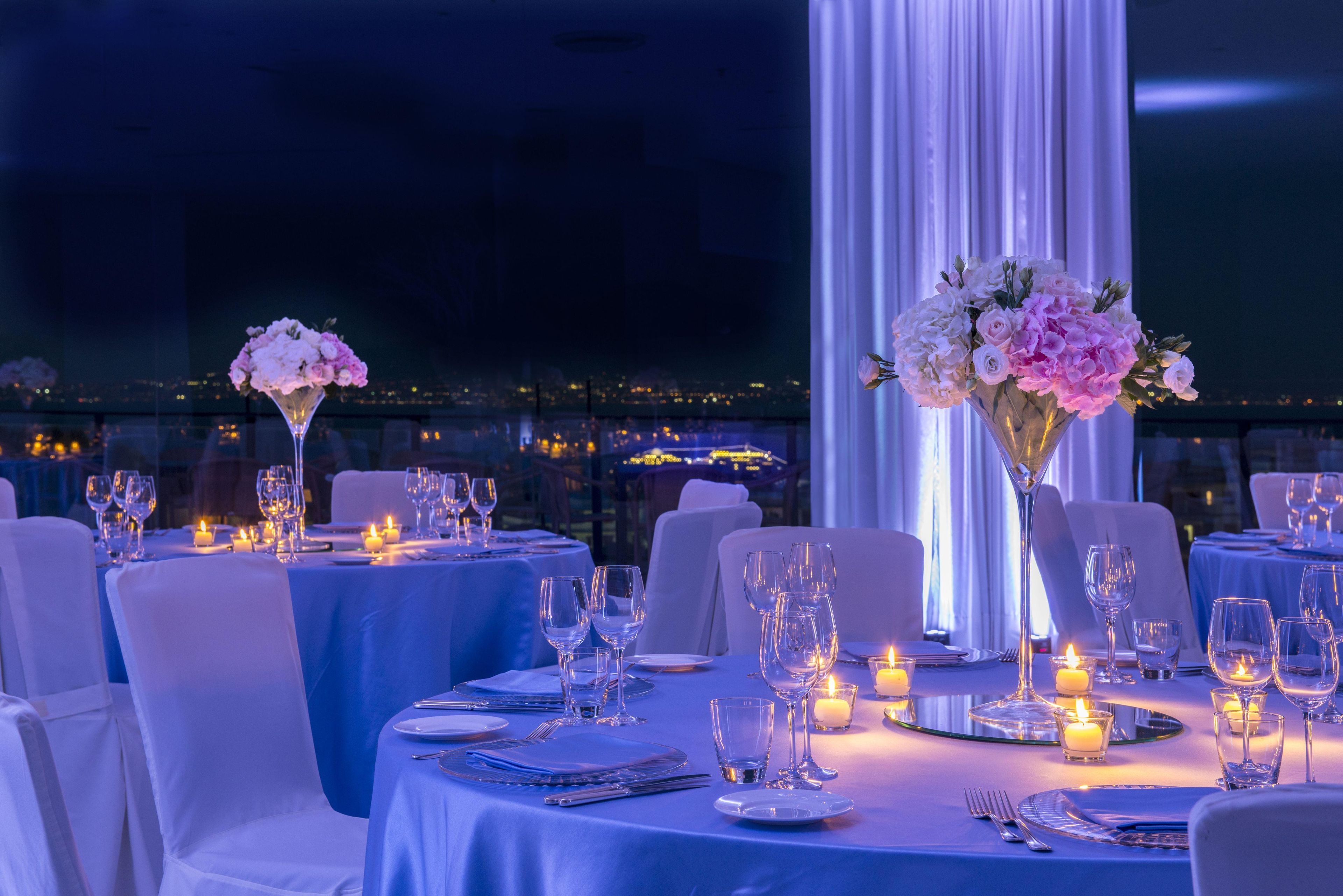 A dining area with tables set for a meal, candles, and floral centerpieces.