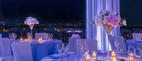 A dining area with tables set for a meal, candles, and floral centerpieces.