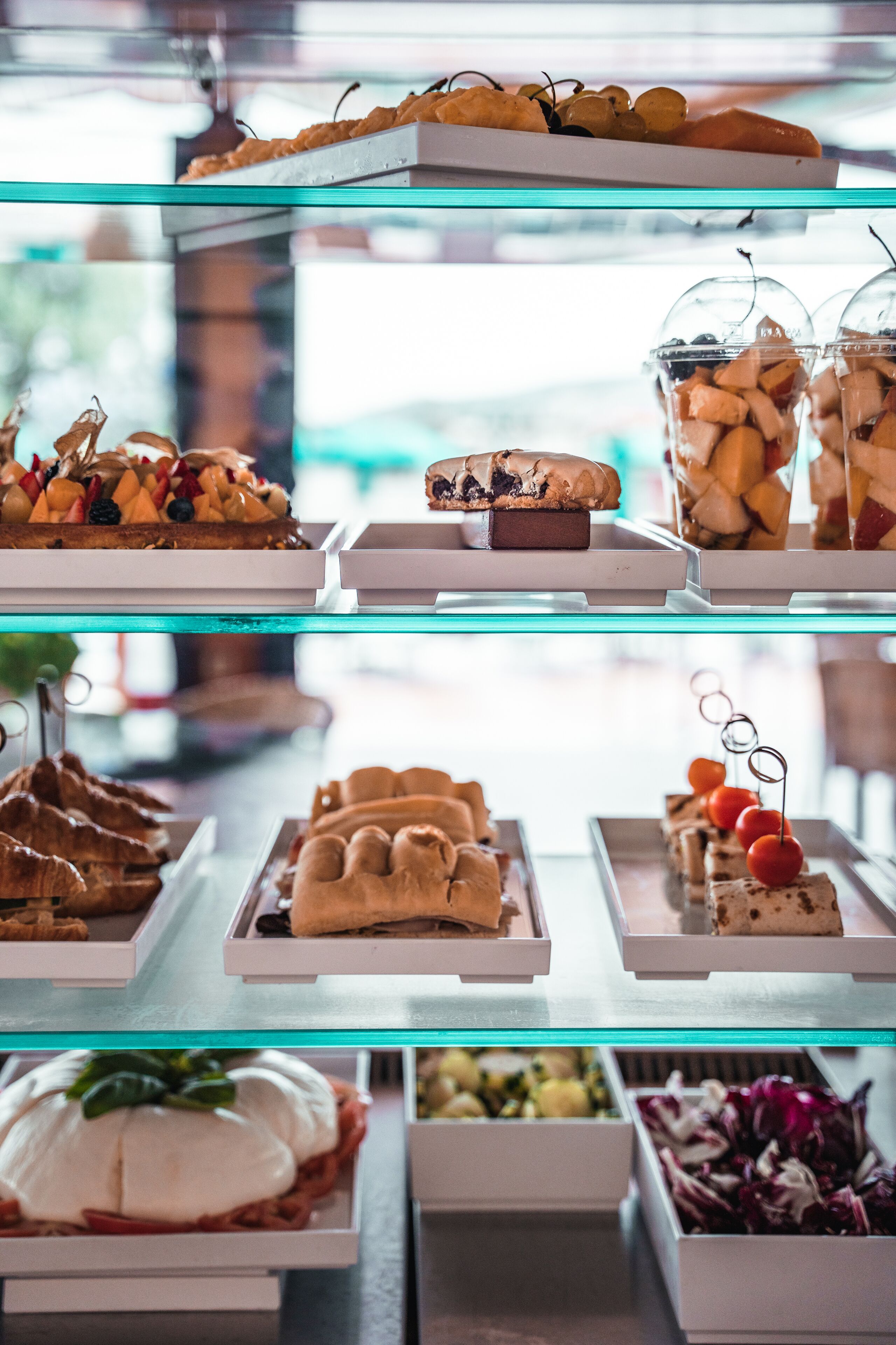 Een meerlaagse presentatie van diverse desserts en gebak in een glazen vitrine.