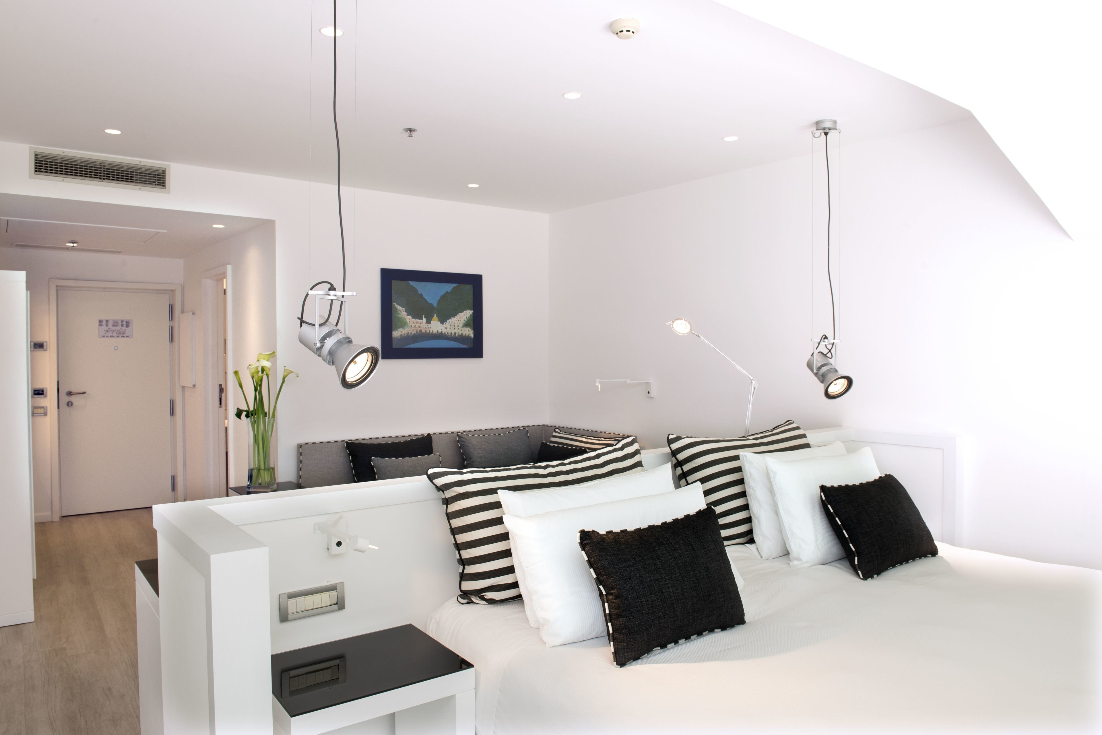 Quarto de hotel moderno com cama, mesas de cabeceira e um quadro na parede.