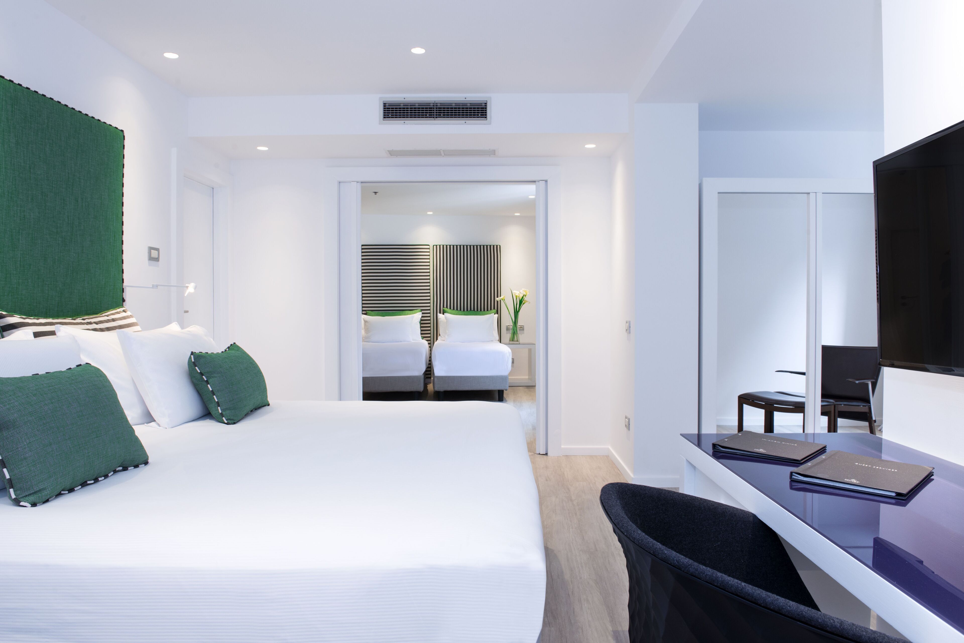 Een moderne hotelkamer met een groot bed, een bureau met stoel en een televisie.