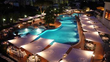 Un resort con varias piscinas, zonas de comedor al aire libre y vistas del pueblo circundante.