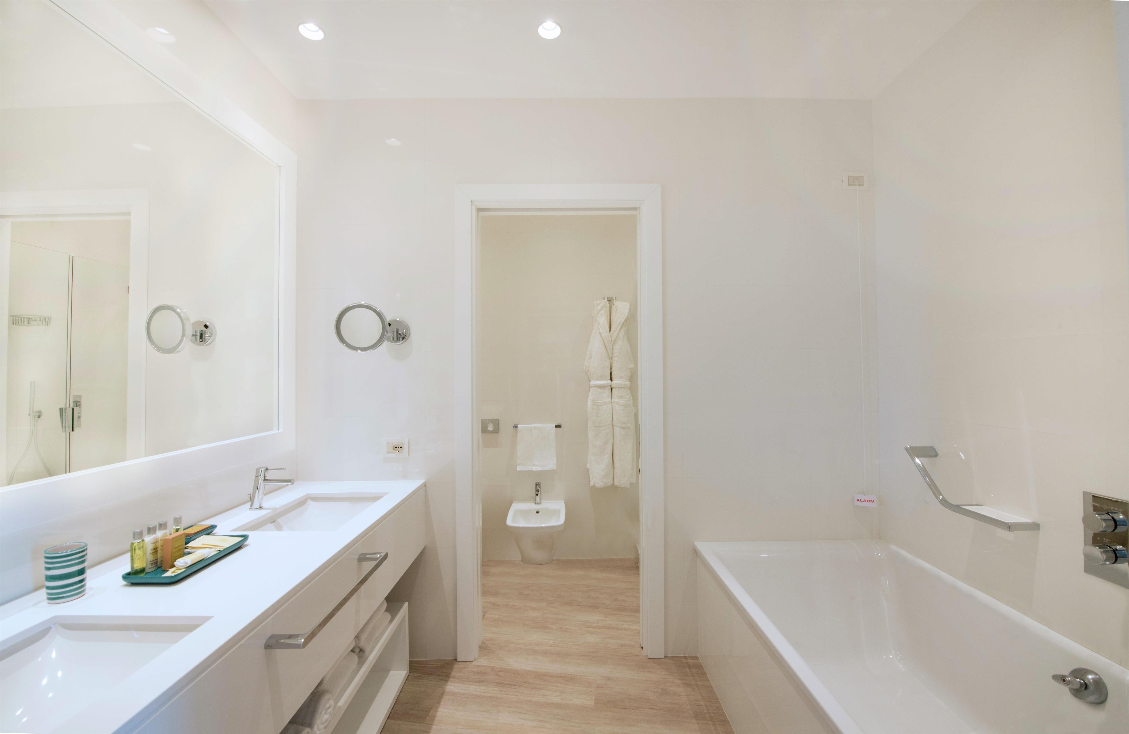 Uma casa de banho moderna com um espelho grande, duas lavatórios, uma banheira e um chuveiro.