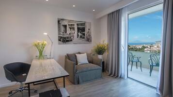 Una habitación moderna con una mesa de comedor, una silla de escritorio, un sofá y un amplio ventanal con vistas a un paisaje urbano.