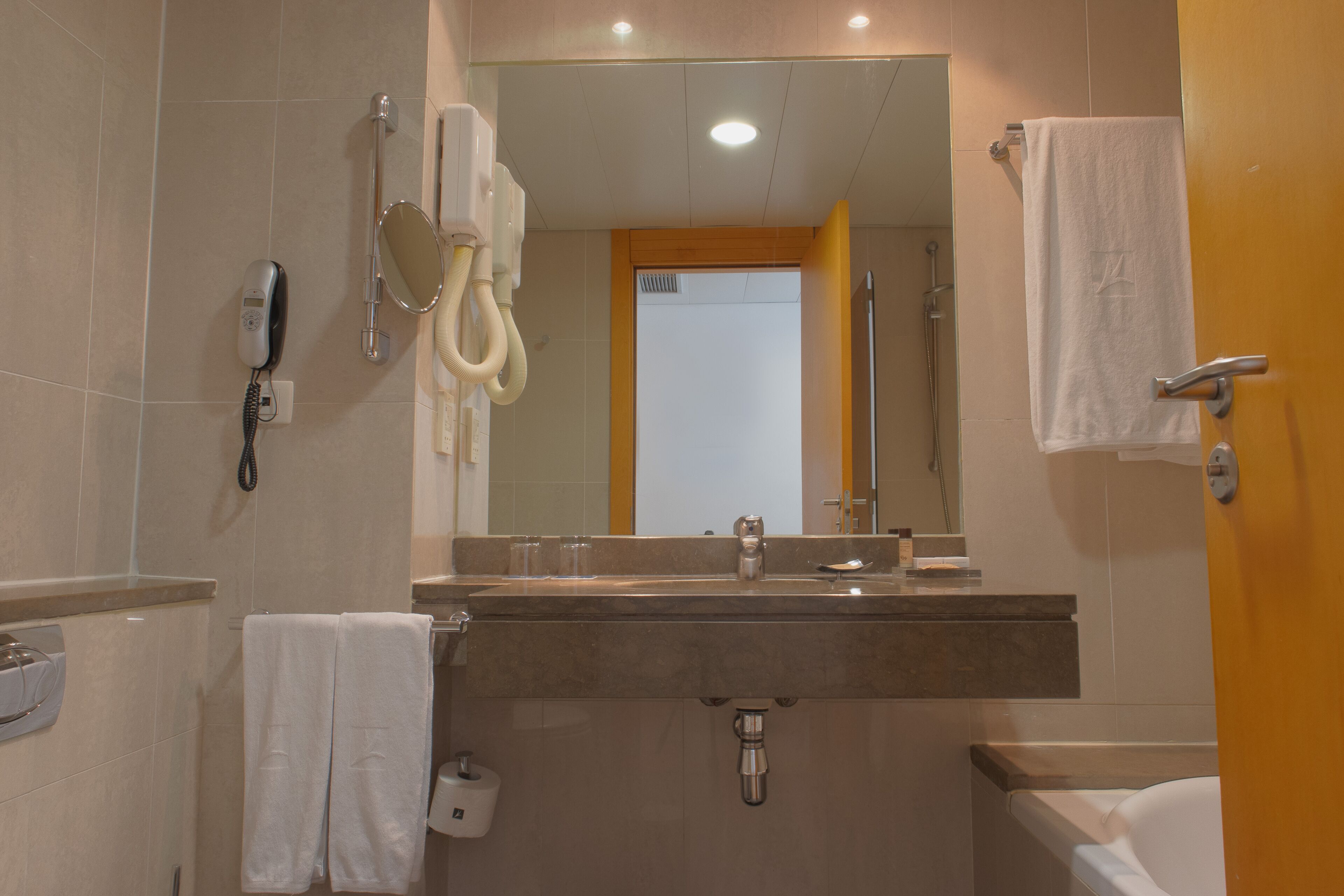 Une salle de bain équipée d’un lavabo, d’un miroir, d’un porte-serviettes et d’un espace douche.