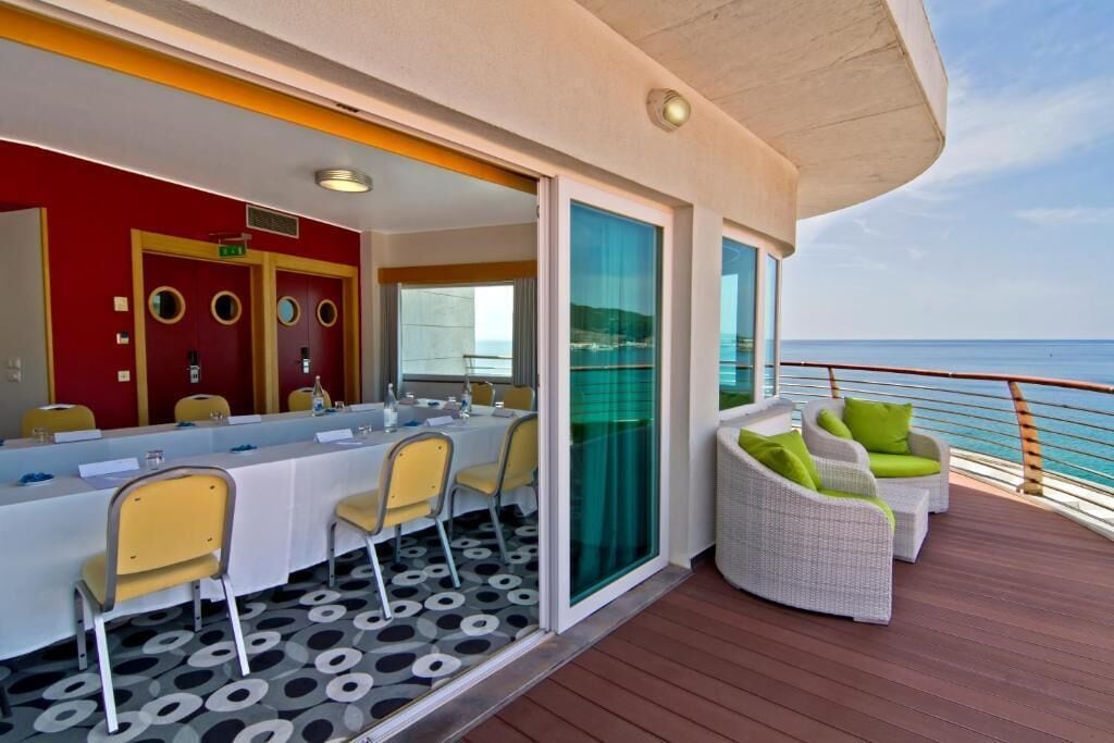 Un terrazzo con tavolo e sedie, una porta vetrata e vista sull'oceano.