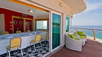 Un terrazzo con tavolo e sedie, una porta vetrata e vista sull'oceano.