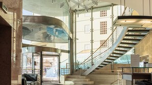 Un interior moderno con una escalera curva, una zona de estar y vistas al exterior.