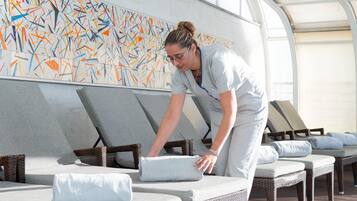 Relax in comfort with wicker lounge chairs and cushioned benches, each equipped with a pillow and towel.