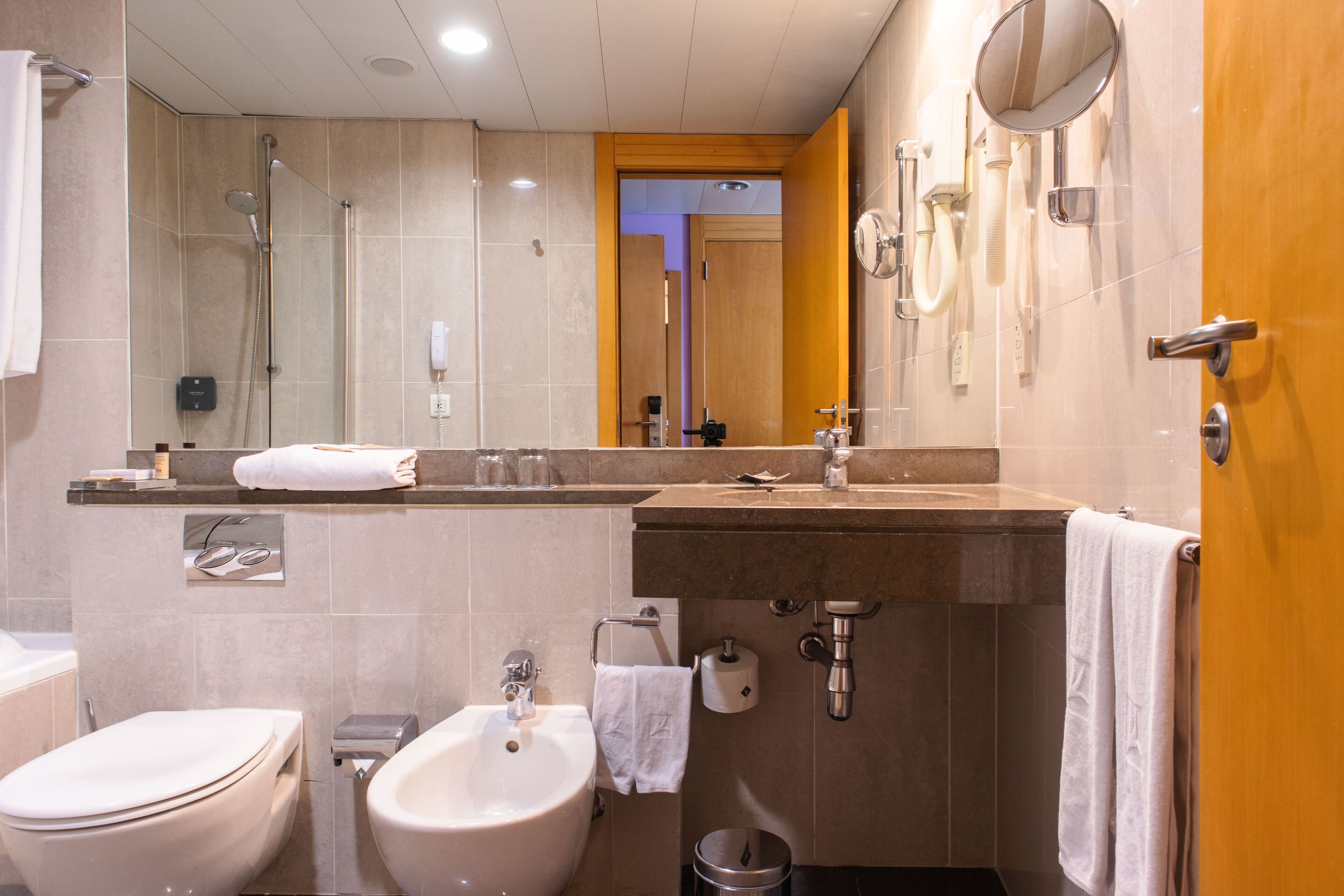 Ein modernes Badezimmer mit Toilette, Bidet, Waschbecken und Dusche.