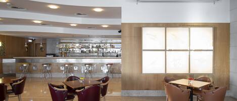 Een modern restaurant met een bar, houten plafond en grote ramen.