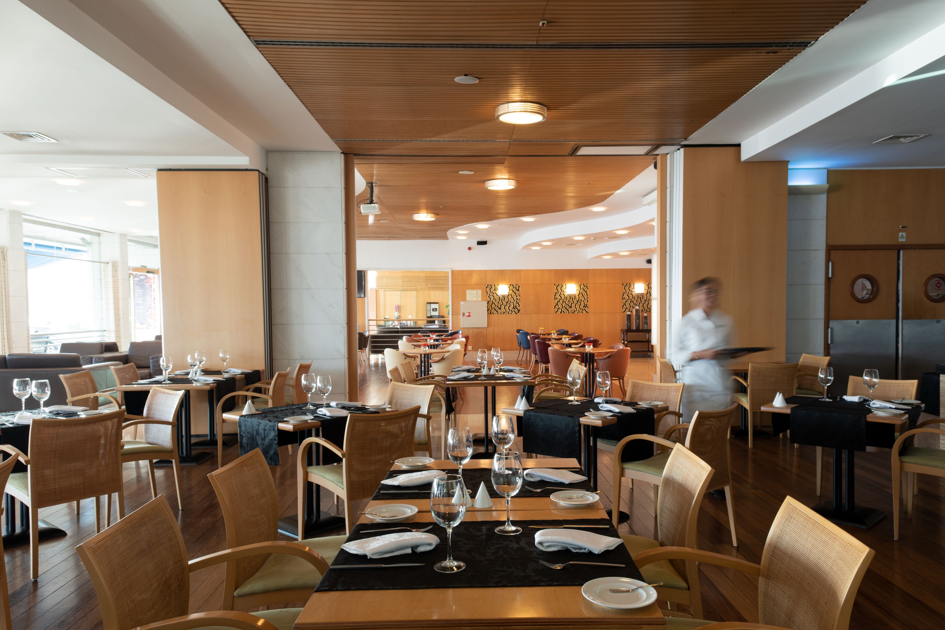 A restaurant with wooden flooring, round tables, and chairs.