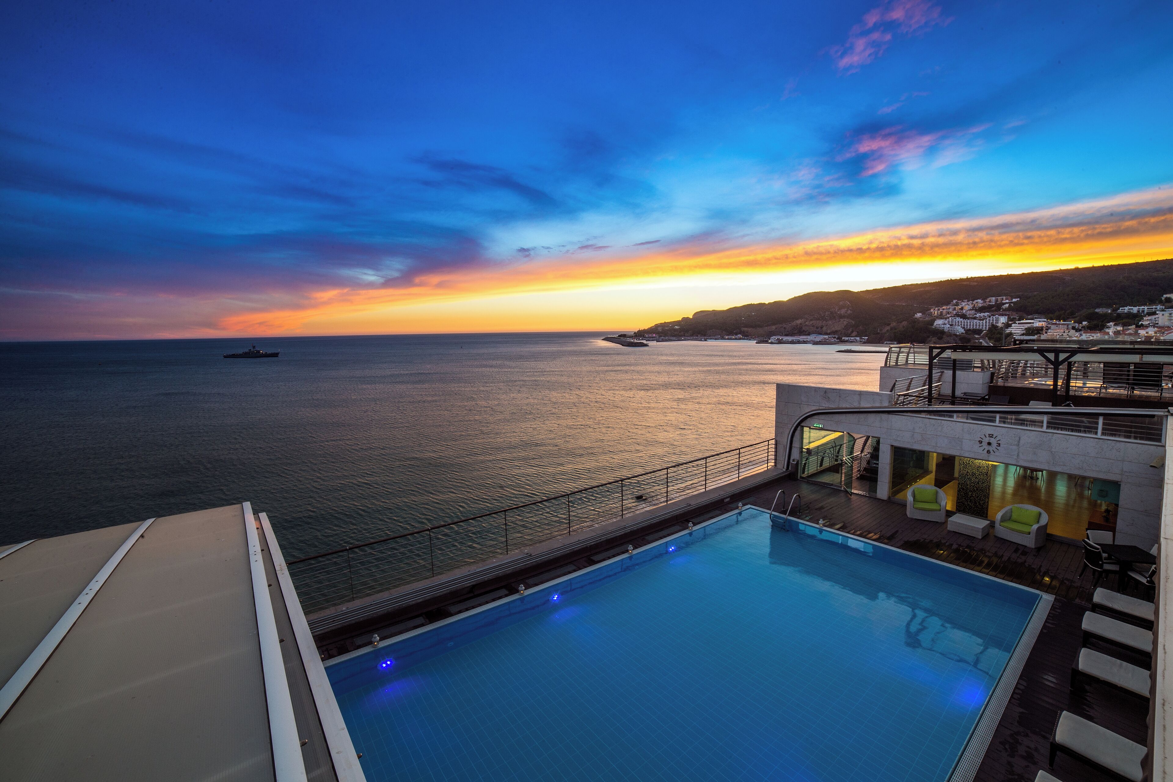 A swimming pool with a view of the sea and sunset.