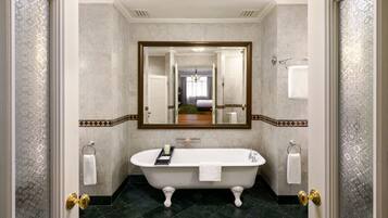 Une salle de bain avec une baignoire sur pieds, un grand miroir et un porte-serviettes.