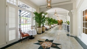 A hotel corridor with a star-patterned floor, white walls, and large potted plants. - Eastern And Oriental Hotel (George Town)