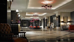 A spacious lobby with a high ceiling, multiple chandeliers, a reception desk, and a seating area with a leather armchair. - Eastern And Oriental Hotel (George Town)