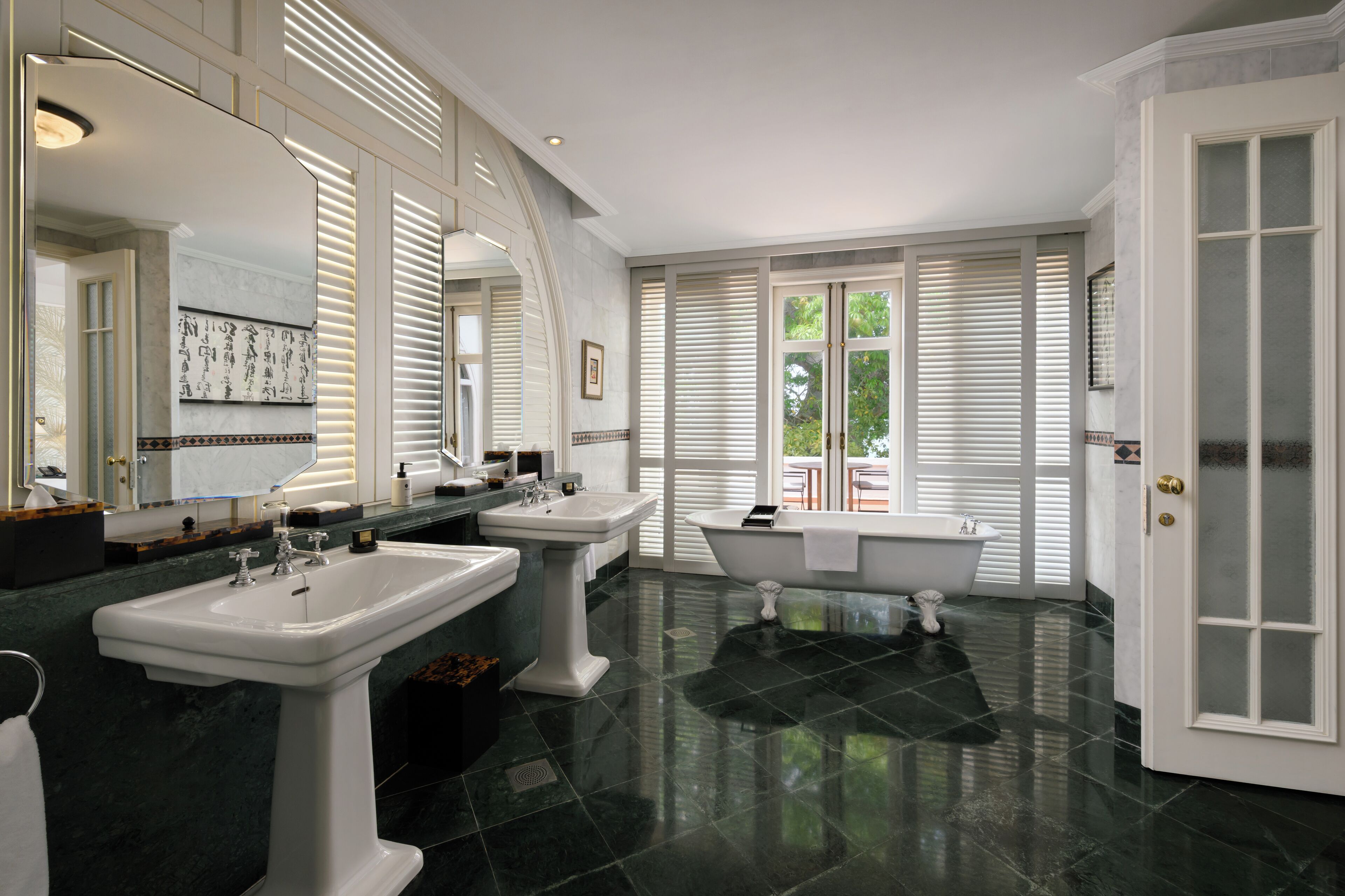 A bathroom with two sinks, a bathtub, and a large mirror.