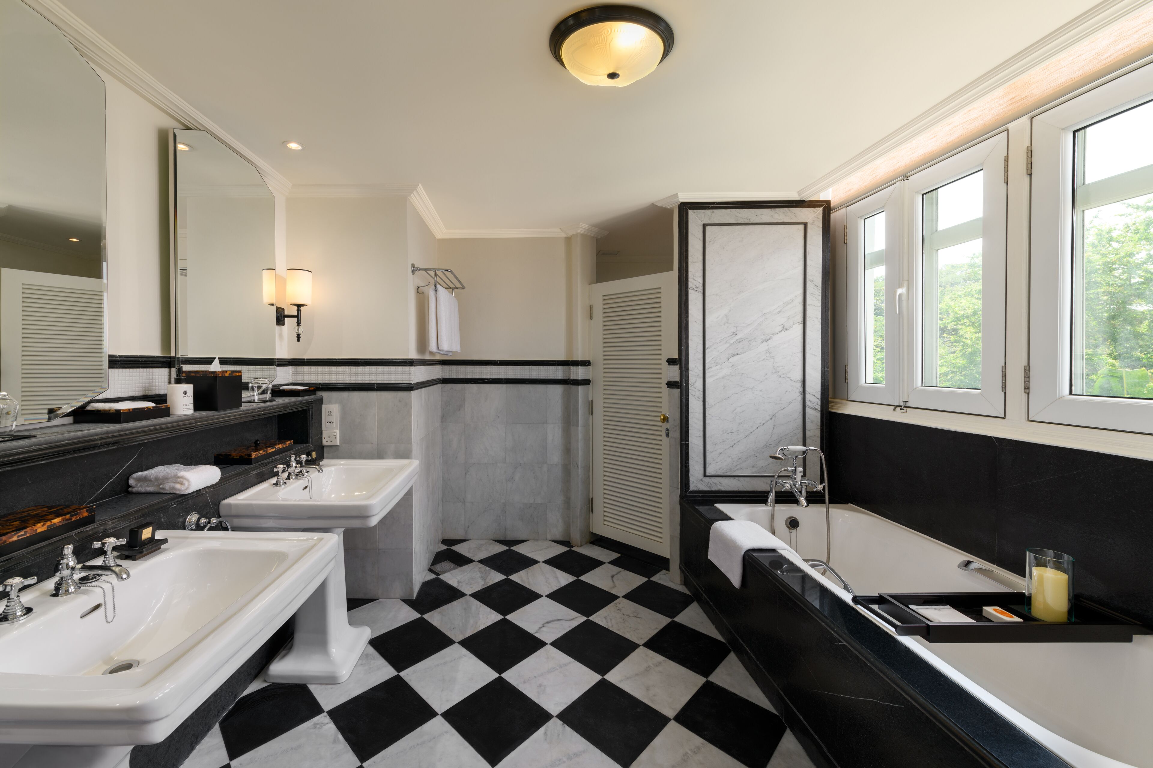 A bathroom with two sinks, a bathtub, and a large mirror.