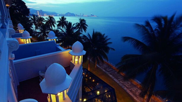 A hotel rooftop with a view of the ocean and palm trees. - Eastern And Oriental Hotel (George Town)