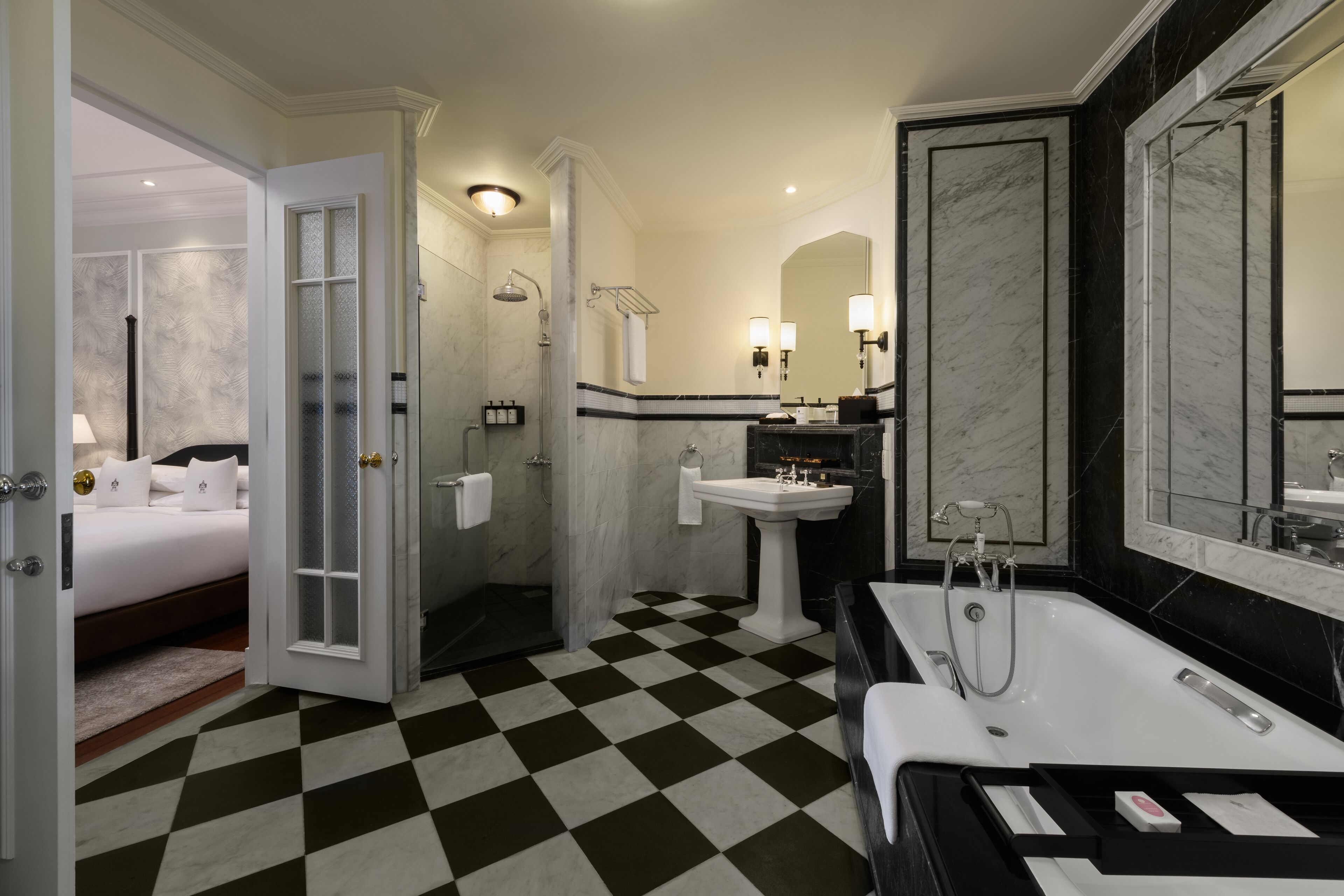 A hotel bathroom with a checkered floor, a large mirror, a bathtub, and a sink.