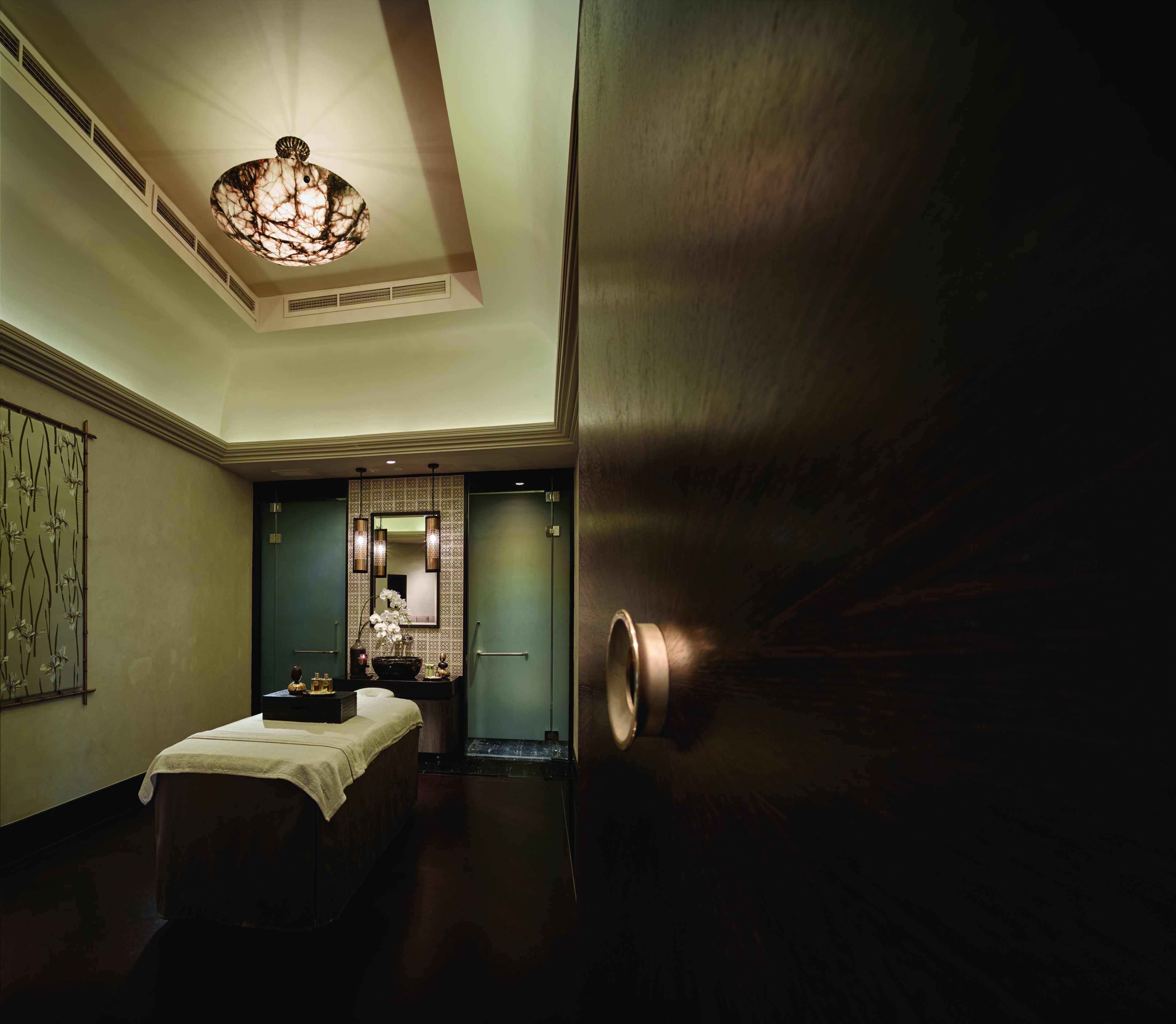 A hotel room with a large bed, a vanity with a mirror, and a chandelier.