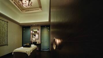 A hotel room with a large bed, a vanity with a mirror, and a chandelier.