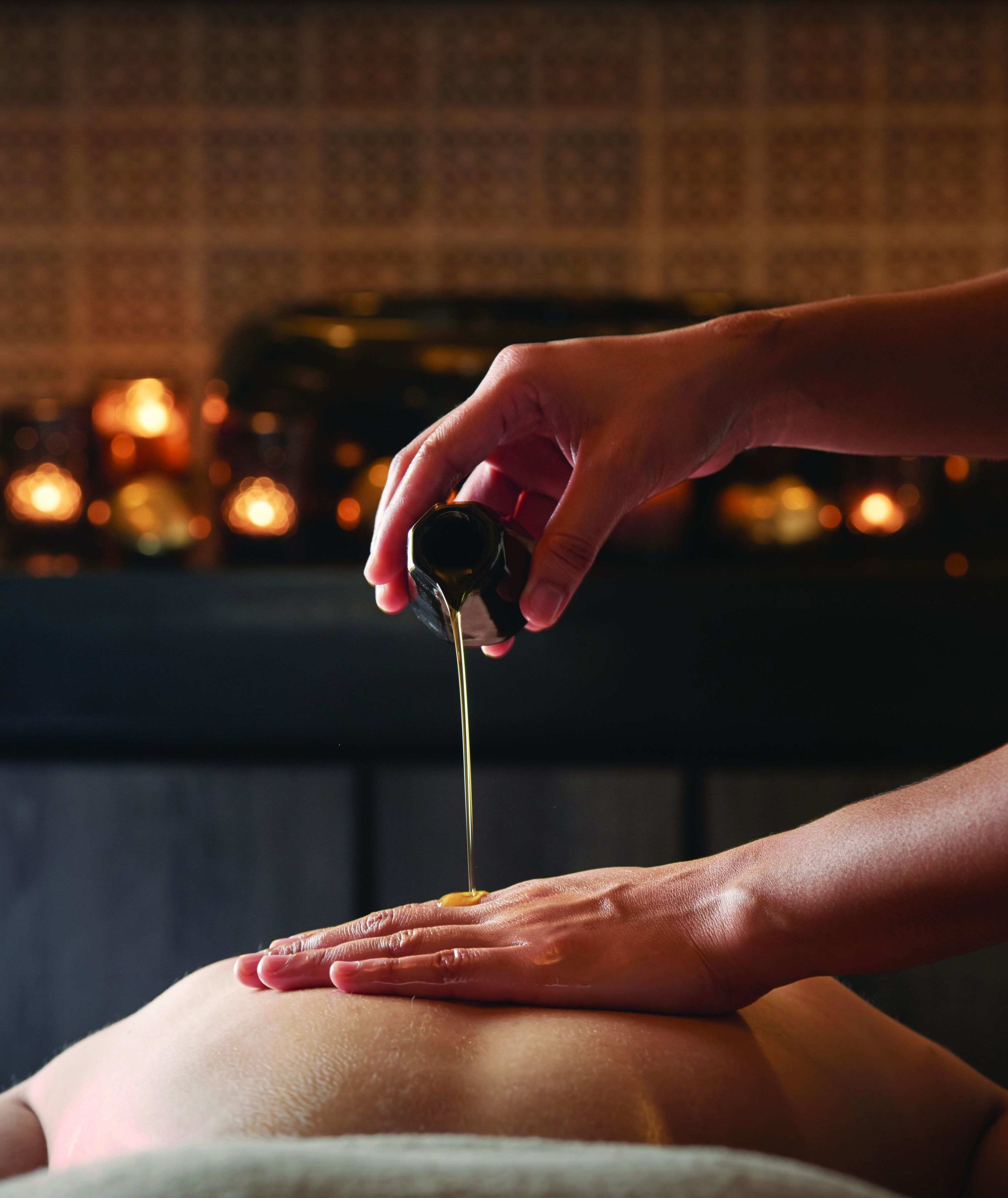 A close-up of a hand pouring a liquid onto a person's back.