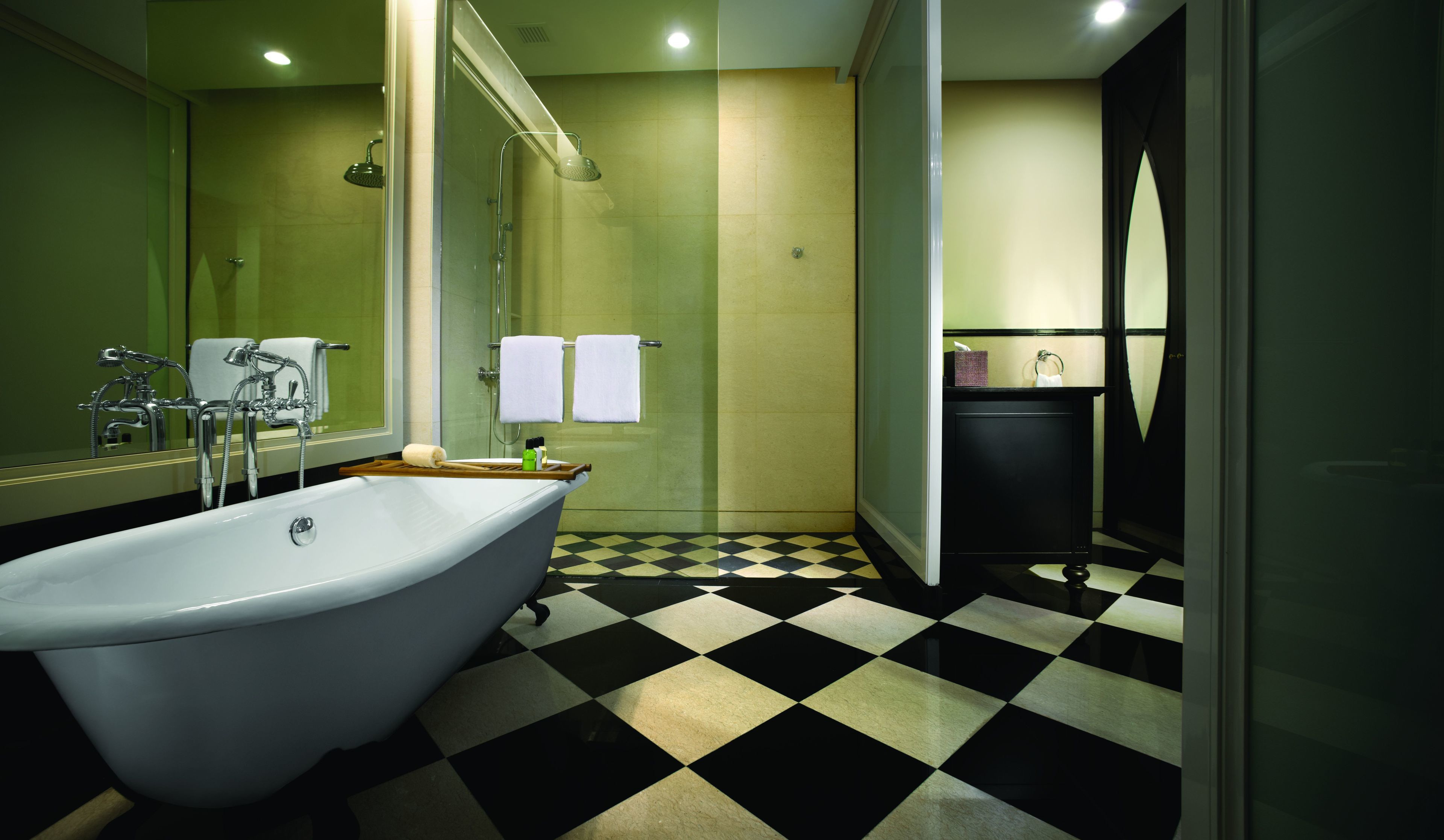 A bathroom with a freestanding bathtub, a glass shower enclosure, and a checkered floor.