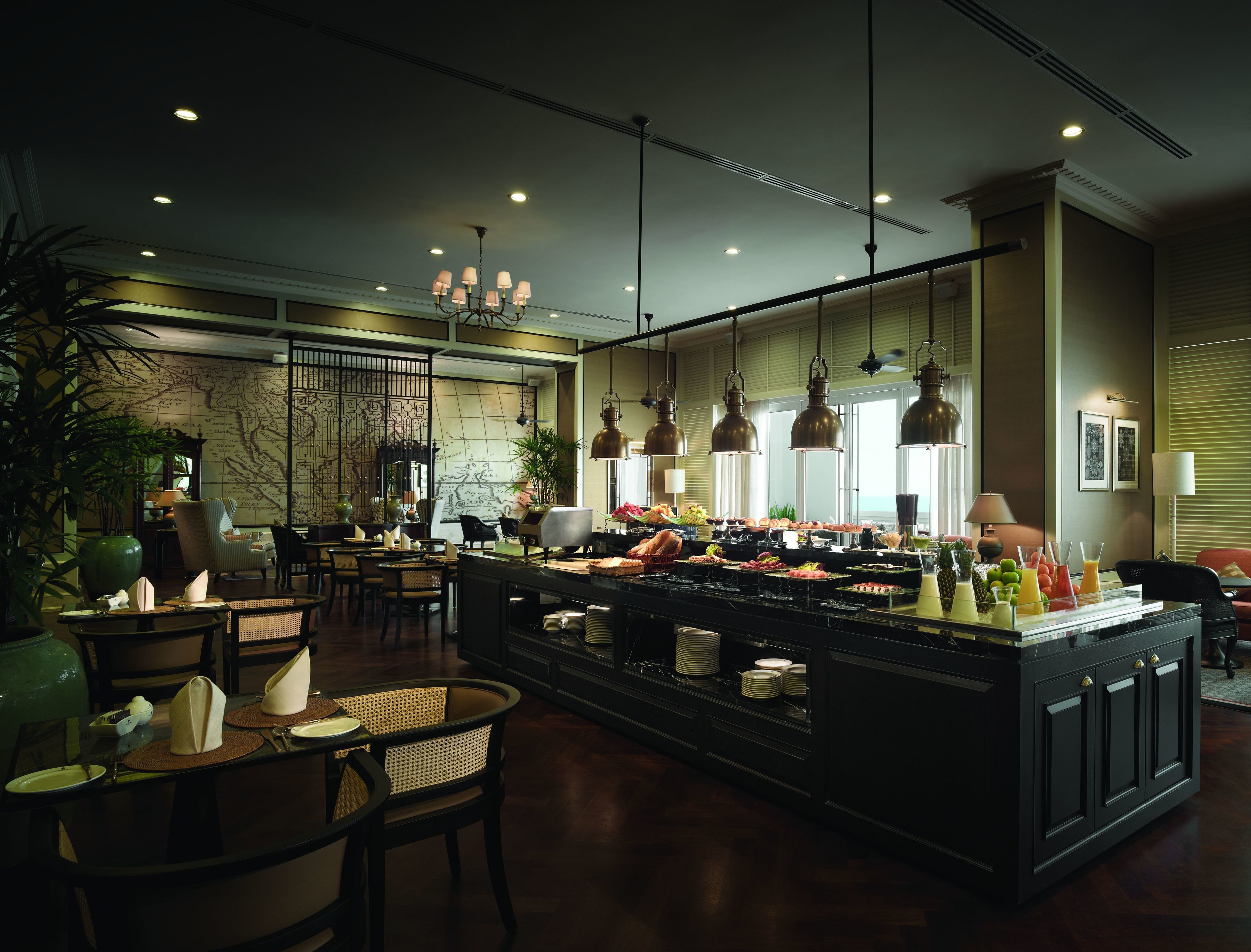 A spacious hotel lobby with a central buffet area, seating arrangements, and a large map on the wall.