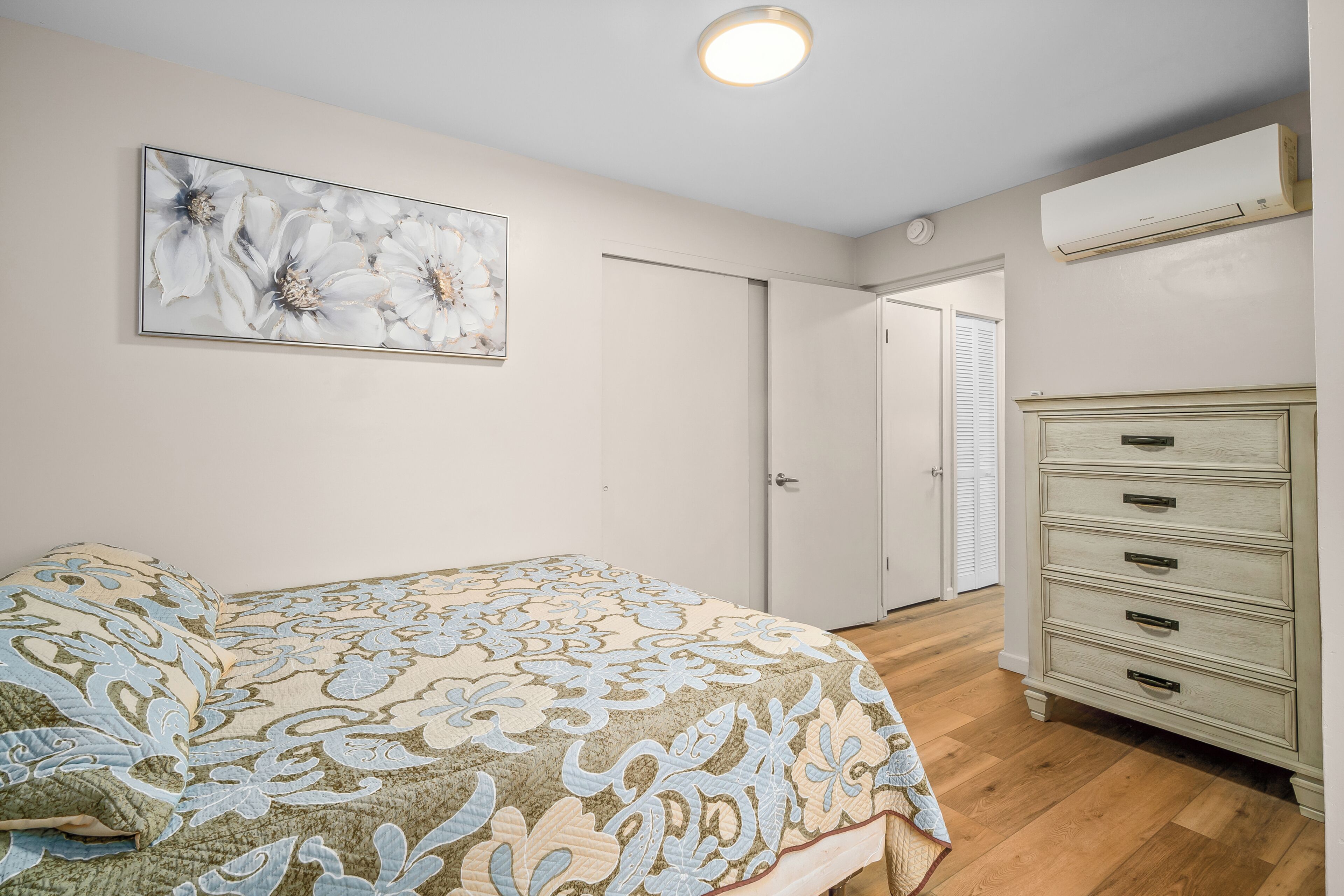 Een slaapkamer met een bed, een dressoir, een deur en een luchtverfrisser aan de muur.