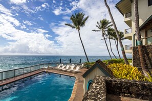 A pool area with lounge chairs and a view of the ocean. - Castle Po'ipū Shores (Koloa)